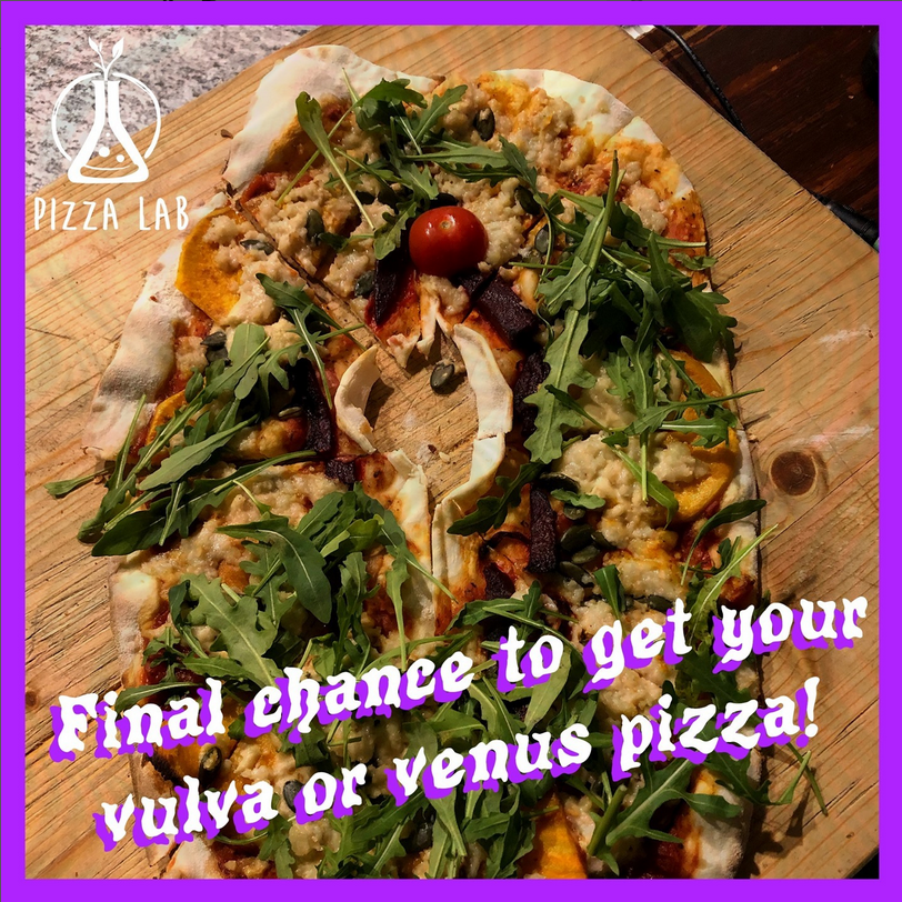 Photograph of a vulva-shaped Pizza with an almond shaped hole in the middle, a tomato symbolizes the clitoris, lots of rocket salad leaves sprinkled over the pizza. In purple and white letters, it reads "Final chance to get your vulva or venus pizza!" 